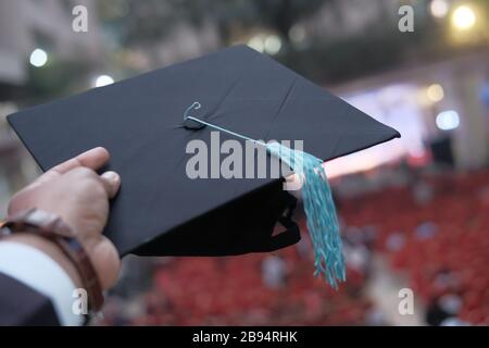 Homme main tenant chapeau de graduation extérieur. Banque D'Images