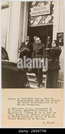 Propagande photographique : le président Laval et Darnand, secrétaire général de la police, quittent le Secrétariat général de la Milice, Vichy. Trampus. 'Photo propagande : le président Laval et Darnand, Secrétaire général du responsable de l'ordre, quitte le secrétariat général de la Milice, Vichy'. VICHY. LE PRÉSIDENT LAVAL,CHEF DU / GOUVERNEMENT PRÉSIDE UNE REUNION / DES CHEFS DEPARTEMENTAUX DE LA / MILICE FRANCAISE. / LE PRÉSIDENT LAVAL, ACCOMPAGNE DE / M. DARNAND, SECRET GÉNÉRAL AU / MAINTIEN DE L'ORDRE ET DE M. BOUT DE / L'AN, SECRET GÉNÉRAL ADJOINT DE / LA MICE FRANCAISE QUITTE Banque D'Images