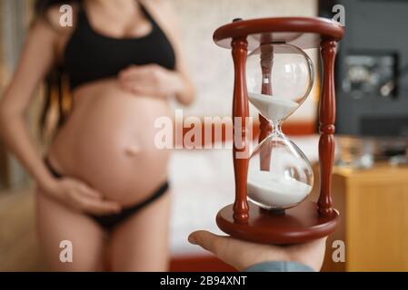 Femme enceinte avec ventre pose contre le verre de sable Banque D'Images