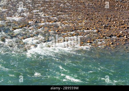 Rivière peu profonde avec eau propre coulant et rochers de gravier rouge et brun en Asie centrale. Paysage naturel montrant le strem d'eau au Kirghizistan. Banque D'Images