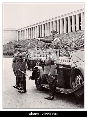 Vintage 1936 propagande nazie Rassemblement de Nuremberg Allemagne Adolf Hitler, portant un brassard de swastika, rend hommage à Heil Hitler au passé de mars du Service du travail de Reich lors de la réunion du Rassemblement du Parti nazi de Zeppelin Fields. Photo avec Adolf Hitler, Konstantin Hierl, le ministre Reich Rudolf Hess et le ministre Reich Wilhelm Frick Banque D'Images