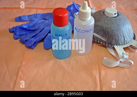 Une paire de gants de chirurgien bleus, un masque filtrant en carbone et un désinfectant pour les mains et l'alcool au milieu, sur une table avec un espace vide au fond. Banque D'Images