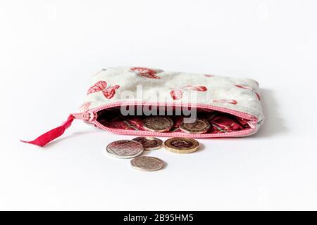Un sac à main en tissu rose à motif papillons et fermeture à glissière ouvert avec pièces britanniques Banque D'Images
