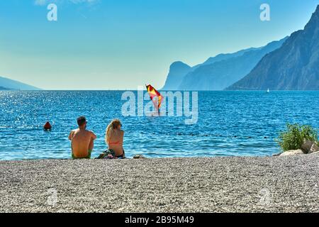 Torbole, Italie-09 octobre 2018 : personnes assises à la plage sur la chaise longue et admirant le lac de Garde en été, vue sur le magnifique lac Banque D'Images