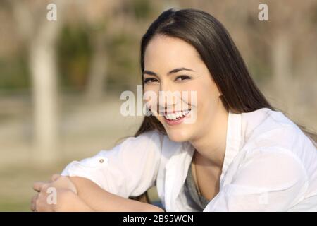 Une heureuse femme vous regarde avec un sourire parfait assis dans un parc une journée ensoleillée Banque D'Images