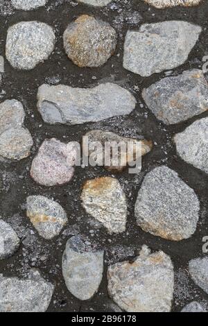 Route en pavés et ciment. Plancher extérieur gris à proximité. Les pierres de trottoir sont asymétriques et la plupart d'entre elles ont des pierres grises. Banque D'Images