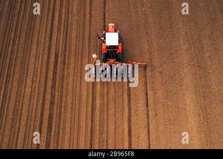 Drone photographie de tracteur avec seeder travaillant dans le secteur des machines agricoles, la plantation est de la semence en terre fraîchement labourés Banque D'Images