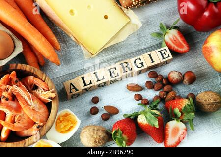 Concept d'allergie alimentaire. Allergie alimentaire comme amandes, lait, fromage, fraise, graines, oeufs, arachides et crustacés ou crevettes avec lettre en bois en allemand Banque D'Images