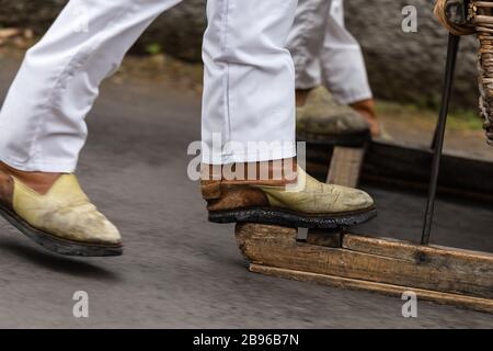 Close up d'un cavalier de la descente, traîneau traditionnel 'carrinhos de cesto', le 'Monte' dans l'île de Madère, au Portugal. Banque D'Images