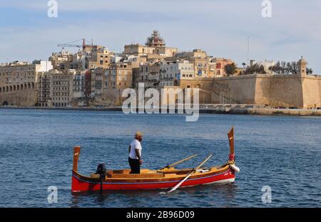 Un homme à bord d'un bateau-taxi maltais traditionnel, appelé dgħajsa, dans le Grand Port près de Senglea, l'une des trois villes. Banque D'Images