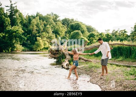 Un jeune couple marchant main dans la main sur une rive. Banque D'Images