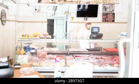 Avetrana, Italie, - 19 mars 2020. Le vendeur sert une viande plus chère, portant un masque médical et des gants de protection pendant l'épidième de Coronavirus. SHOPP Banque D'Images