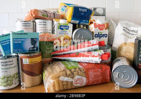 Boîtes et sachets de nourriture séchée empilés sur la surface de travail de la cuisine après la livraison à la maison. Stockage dû à la pandémie de Coronavirus. Banque D'Images