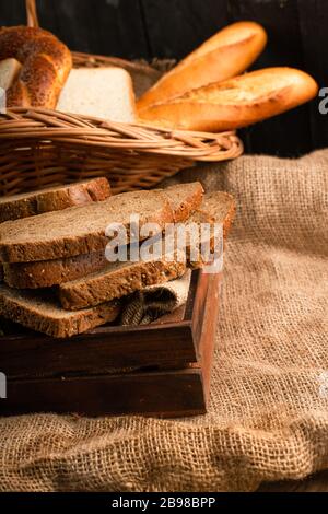 Tranches de pain brun dans la boîte et bagels avec baguette dans le panier Banque D'Images