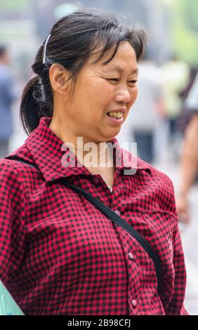 Chongqing, Chine - 9 mai 2010 : centre-ville. Près de la poitrine et de la tête d'une femme avec des cheveux noirs et une chemise à carreaux rouge-noir. Banque D'Images