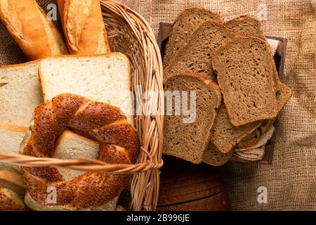 Tranches de pain brun dans la boîte et bagels avec baguette dans le panier Banque D'Images