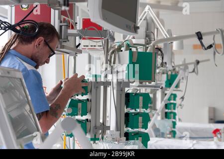 L'infirmière mâle vérifie la fonction de la pompe à perfusion de seringue en unité de soins intensifs à l'hôpital. Banque D'Images