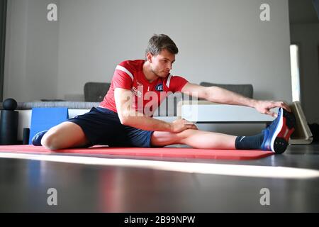 Karlsruhe, Allemagne. 23 mars 2020. Benjamin Uphoff, gardien de but du second club de division Karlsruher SC, effectue des exercices d'étirement dans son appartement. En raison de l'annulation des séances de formation, le gardien doit également rester à la maison jusqu'à nouvel ordre. En plus des unités de course, il fait des exercices de stabilité et un petit programme de force. (À dpa: 'Skipping and cyclisme dans le bureau à domicile - Comment les gardiens de but KSC garder l'ajustement') crédit: Uli Deck/dpa/Alay Live News Banque D'Images