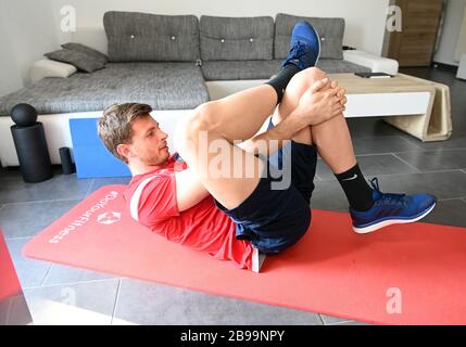 Karlsruhe, Allemagne. 23 mars 2020. Benjamin Uphoff, gardien de but du second club de division Karlsruher SC, effectue des exercices d'étirement dans son appartement. En raison de l'annulation des séances de formation, le gardien doit également rester à la maison jusqu'à nouvel ordre. En plus des unités de course, il fait des exercices de stabilité et un petit programme de force. (À dpa: 'Skipping and cyclisme dans le bureau à domicile - Comment les gardiens de but KSC garder l'ajustement') crédit: Uli Deck/dpa/Alay Live News Banque D'Images