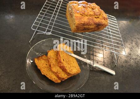 Tranches de pain de citrouille fait maison sur plaque transparente coupée avec couteau de pain sur la grille de refroidissement, sur comptoir noir Banque D'Images