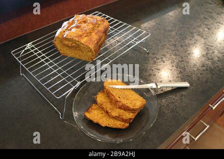 Tranches de pain de citrouille fait maison sur plaque transparente coupée avec couteau de pain sur la grille de refroidissement, sur comptoir noir Banque D'Images