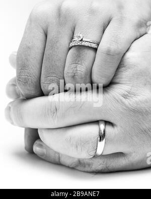 gros plan sur les mains d'un couple portant leurs bandes de mariage éditées en noir et blanc pour un effet doux Banque D'Images