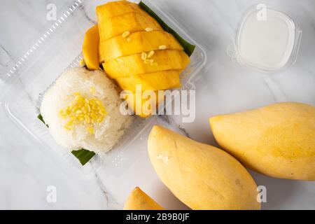 Voici la photo de mangues de riz sticky avec du lait de noix de coco sur le sable Banque D'Images