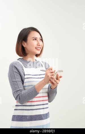 Portrait de la tête de la serveuse souriante portant un tablier noir prêt à prendre commande client, femme attrayante avec ordinateur portable et stylo dans les mains regardant CA Banque D'Images