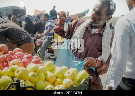 Vendeur de fruits iranien utilisant une balance de pesage à suspension manuelle pour vendre des marchandises sur le marché de Minab Thursday, en Iran. Banque D'Images