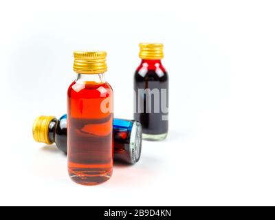 Coloration alimentaire dans les bouteilles de verre sur fond blanc isoler, jaune, bleu, rouge, trois bouteilles de coloration alimentaire Banque D'Images