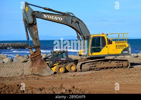 Digger de front en mouvement de la Terre jaune jouant avec un ami jaune plus petit pour des raisons de sécurité Banque D'Images