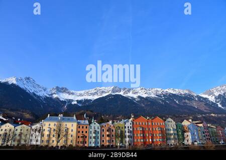 Rangée de maisons colorées lumineuses le long de la rivière l'auberge à Innsbruck, Autriche avec des sommets majestueux de montagne couverts de neige en arrière-plan Banque D'Images