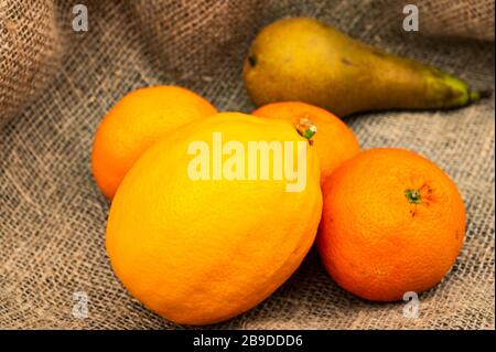 Citron, mandarines et poire sur fond de tissu texturé. Gros plan Banque D'Images