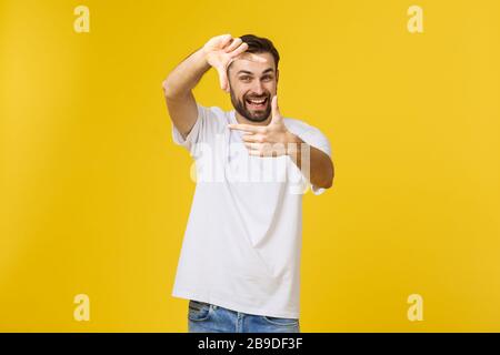 Portrait d'un homme d'affaires souriant faisant un cadre avec les doigts et regardant l'appareil photo sur fond jaune Banque D'Images