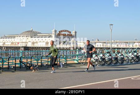 Brighton Royaume-Uni 24 mars 2020 - les coureurs avec leur chien prenant l'exercice le long du front de mer de Brighton sur une belle matinée ensoleillée alors que les nouvelles restrictions gouvernementales se présentent pendant la crise pandémique de Coronavirus COVID-19 . Crédit: Simon Dack / Alay Live News Banque D'Images