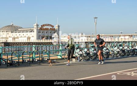 Brighton Royaume-Uni 24 mars 2020 - les coureurs avec leur chien prenant l'exercice le long du front de mer de Brighton sur une belle matinée ensoleillée alors que les nouvelles restrictions gouvernementales se présentent pendant la crise pandémique de Coronavirus COVID-19 . Crédit: Simon Dack / Alay Live News Banque D'Images