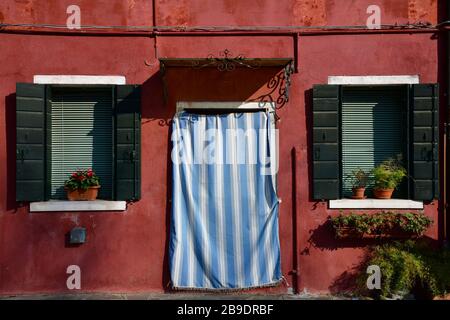 Fermez la porte d'entrée et deux fenêtres et volets de la maison rouge pâle à Burano Banque D'Images