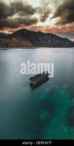 Un hangar à bateaux en bois traditionnels reflétant sur l'eau cristalline de la Almsee, près de Grünau im Almtal, Oberösterreich, Autriche Banque D'Images