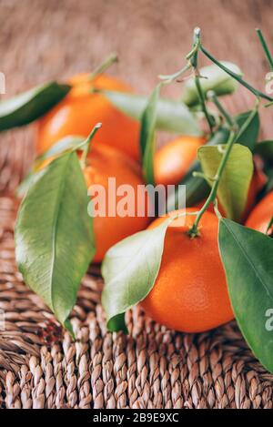 Mandarine ou clémentine avec des feuilles de palmier vertes sur fond de rotin. Espace de copie. Concept de Noël ou de nouvel an.