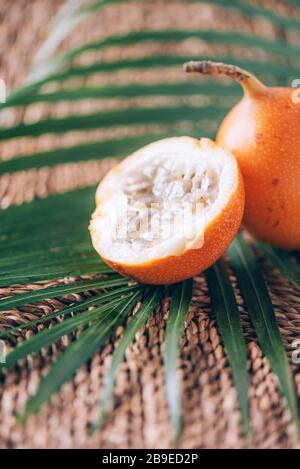 granadilla douce ou grenadia avec feuilles de palmier sur fond de rotin. Espace de copie. Bannière de création. Heure d'été. Cuisine exotique, conce aux fruits tropicaux Banque D'Images