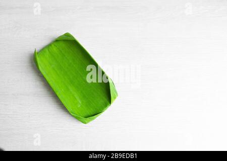 Feuille verte d'une banane. Plats écologiques à usage alimentaire. Cadre en carton enveloppé dans une feuille de banane. Plaque écologique. Banque D'Images