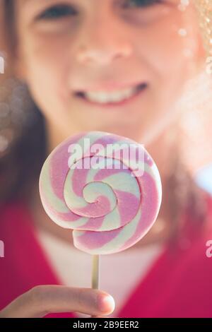 Petite fille dans un chapeau de paille avec un lollipop rose et blanc - peu profonde profondeur de champ - se concentrer sur la lollipop Banque D'Images