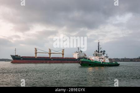 Cobh, Cork, Irlande. 24 mars 2020. Le transporteur en vrac de Riga Ocean Breeze est escorté hors du port à l'aube par le remorqueur DSG Alex à Cobh, Co. Cork, Irlande. - crédit; David Creedon / Alay Live News Banque D'Images