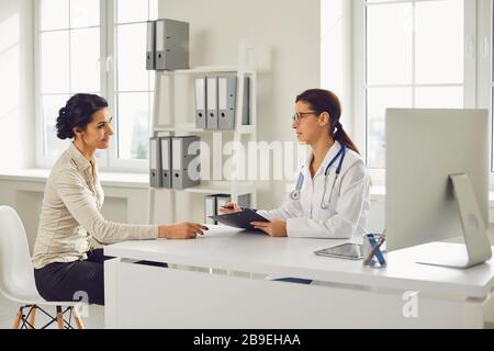 Médecin femme pédiatre gynécologue parlant client assis à une table dans un bureau de clinique. Banque D'Images