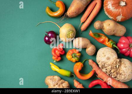 Des légumes biologiques à la mode et laid. Assortiment d'aubergines fraîches, oignons, carottes, courgettes, pommes de terre, citrouille, poivre dans un sac en papier artisanal sur le nègre vert Banque D'Images