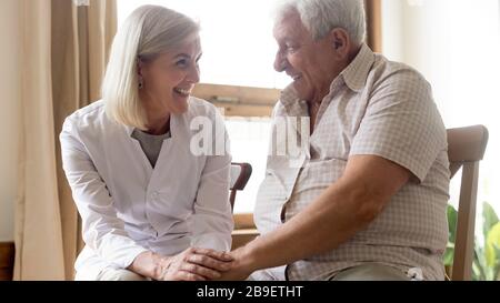 Un médecin souriant et sympathique tenant des mains de patients plus âgés et heureux Banque D'Images