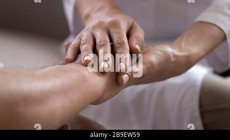 Gros plan sur le personnel soignant tenant les mains plus anciennes du patient, montrant un soutien Banque D'Images