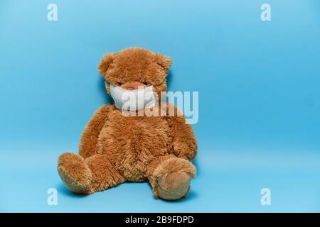 Un grand ours en peluche marron dans un masque est isolé sur un fond bleu Banque D'Images