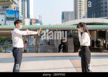 Une femme d'affaires asiatique malade tousse avec masque et homme d'affaires cesser de signer lui main pour garder la distance de protection contre les virus COVID-19 et les personnes social distancing Banque D'Images