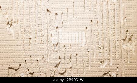 Colle pour une tuile avec un modèle d'engrenage. Installation de tuiles. La surface du mur est recouverte de pâte adhésive avant de poser des tuiles ou des s décoratifs Banque D'Images